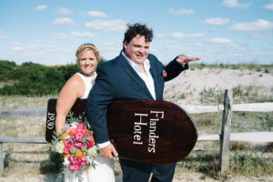 bride and groom holding wooden boogie board on beach