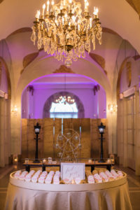 Hall of mirrors decorated with beachy placecard table and pink lighting